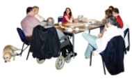 A group of people with different disabilities sitting around a table talking. There is an assistance dog nearby.
